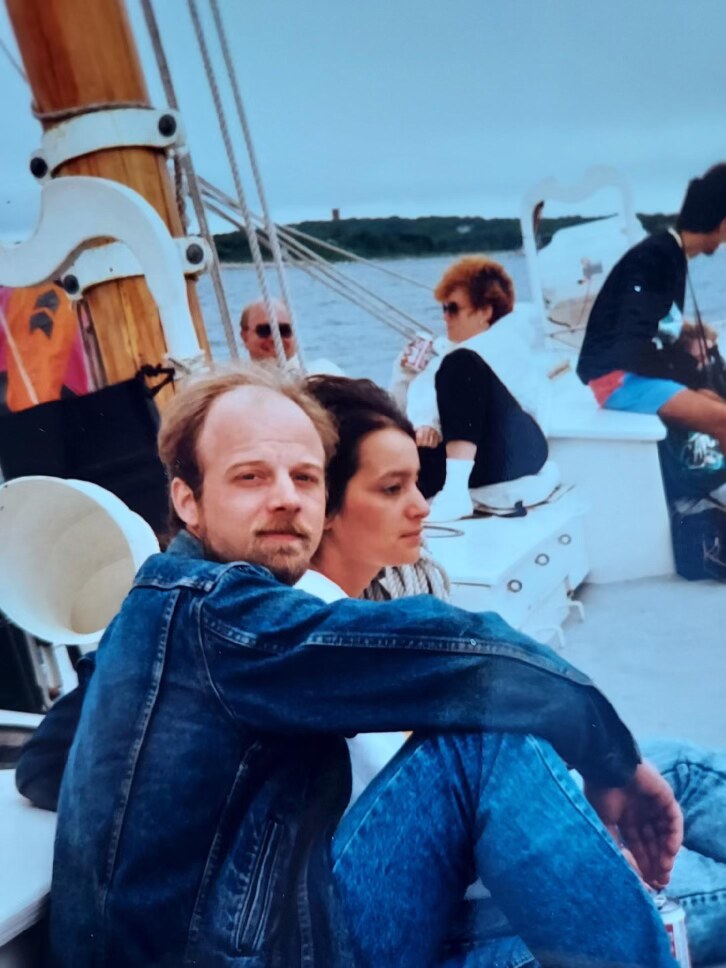 David in a denim jacket sitting beside a woman on a boat