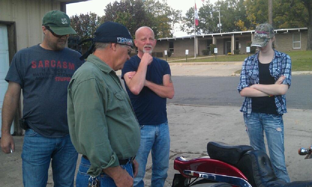 David gathered outdoors with family beside a motorcycle